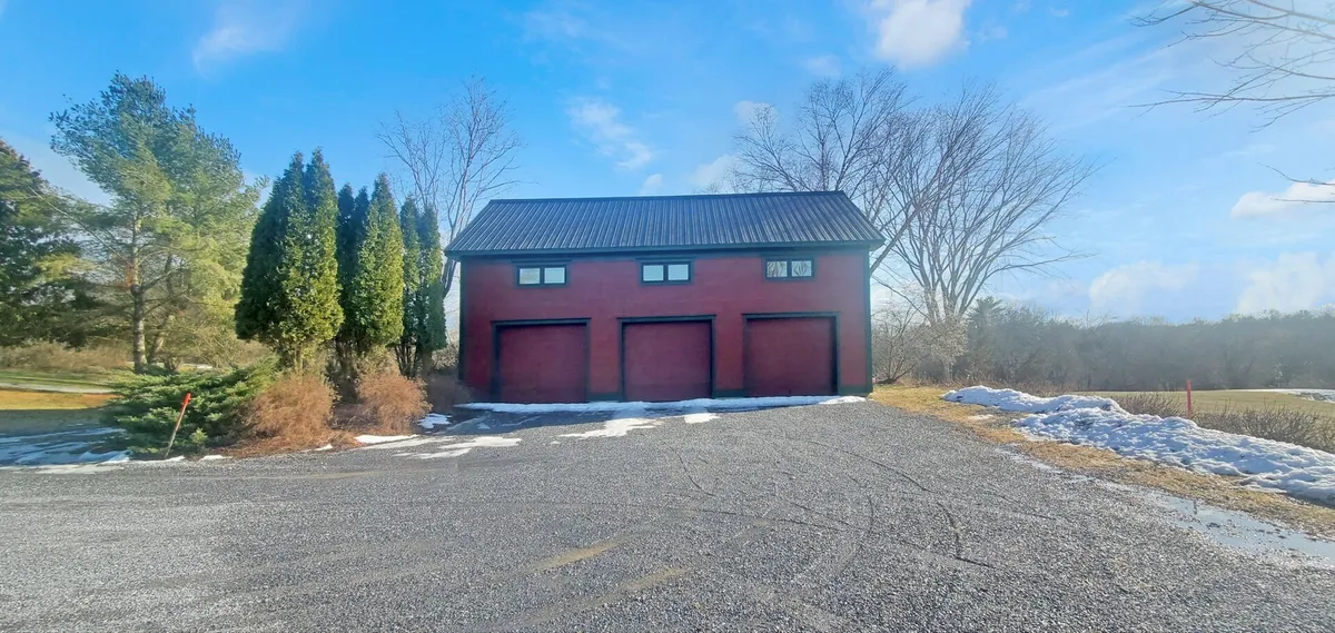A clear view of the three-bay garage set against the estate’s red brick facade and green surroundings. The generous driveway provides ample space for visitors and adventure gear, reinforcing the estate’s practical amenities for active families.